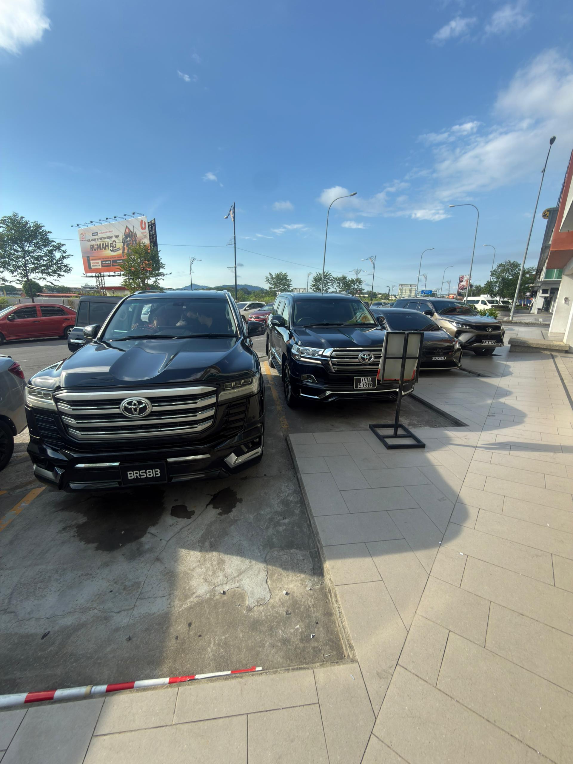 ZahraGO Toyota Land Cruiser and rental fleet parked along a street in Kota Kinabalu